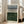 May include: Large framed abstract art print leaning against white wall next to beige upholstered chair. The artwork features horizontal black lines across the center with a gray watercolor wash above and deep green watercolor section below, creating a minimalist landscape effect. Natural wood frame with white matting, positioned on light wooden floors in bright, airy room with tall windows.