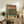 May include: Framed vintage-style Japanese poster featuring turntable and headphones in retro green, orange and cream color scheme, displayed on rustic wooden sideboard alongside books, ceramic vase, and fern plant in cozy living room setting with leather armchair
