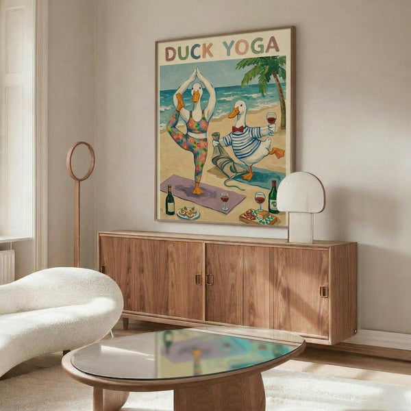 May include: Framed poster showing two cartoon ducks doing yoga poses on a beach scene with wine glasses and food, displayed above a walnut wood credenza in a modern living room with white curved chair, glass coffee table, and floor lamp.