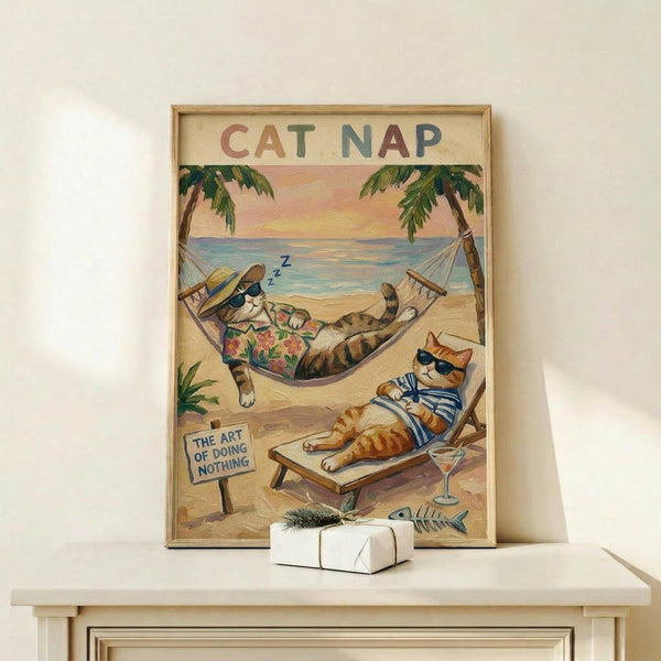 May include: Framed poster showing two cartoon cats relaxing on a tropical beach - one sleeping in a hammock wearing Hawaiian shirt and hat with "Z" sleep bubble, another lounging on beach chair with sunglasses and striped shirt holding cocktail. Palm trees frame ocean sunset scene. Small sign reads "The Art of Doing Nothing." White gift box with greenery sits on light wood shelf below cream-matted artwork in natural wood frame against white wall.