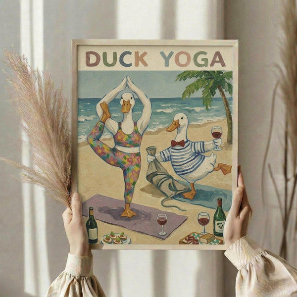 May include: Hands holding a framed poster showing two white ducks doing yoga poses on a beach. One duck wears colorful patterned leggings in a tree pose, the other wears striped shirt sitting cross-legged. Scene includes yoga mats, wine bottles, glasses, appetizers, palm tree, and ocean backdrop. Light wooden frame against white curtained window with dried wheat stems visible.
