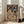 May include: Framed poster artwork displaying two cartoon cats in astronaut suits sitting at a dinner table on a planetary surface. Orange tabby cat holds freeze-dried tuna while black cat has galaxy bubbles. Space milk carton and various space foods scattered on table. Starry galaxy background with rocket ship and Earth visible. Vintage-style illustration in warm colors. White frame leaning against beige sofa in bright living room with large windows.