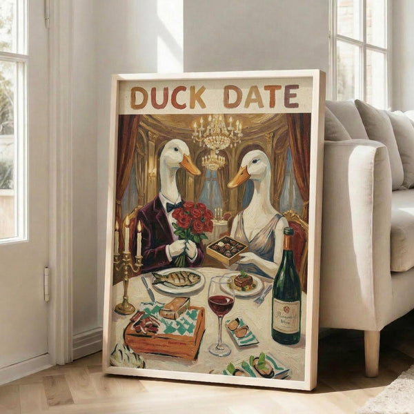 May include: Framed poster leaning against white wall next to beige couch showing two white ducks with orange beaks dressed formally at elegant dinner table. Male duck in purple tuxedo holds red roses, female duck in dress. Table set with wine, chocolates, fish dinner, and candles in ornate room with chandelier. Vintage illustration style with "DUCK DATE" text at top.