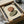May include: Abstract art print featuring two overlapping oval shapes in earthy tones - a warm terracotta brown oval above and sage green oval below on cream background. Framed artwork shown in black frame being unpacked from cardboard box with protective tissue paper and wooden dowels visible around shipping materials.