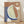 May include: Framed abstract artwork leaning against white wall on light wooden floor. The poster features organic curved shapes in terracotta orange, sage green, and navy blue with white outlines, plus a pale yellow circular moon shape in upper right corner. Blue patterned texture appears on left side. Natural wood frame surrounds the composition. Soft natural lighting creates gentle shadows on the white textured wall.