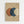 Geometric abstract artwork featuring three overlapping circles in terracotta orange, deep blue, and cream colors on a tan textured background. The minimalist composition is displayed in a light wood frame hanging on a white wall, with the circles creating subtle layered intersections and a balanced modern aesthetic.