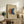 May include: Framed abstract art print featuring three overlapping circles in terracotta orange, navy blue, and cream on beige textured background, displayed on rustic wooden sideboard alongside fern plant, stacked books, and ceramic vases in warm neutral living room setting with white walls and soft natural lighting.