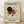 May include: Framed abstract geometric art print in light wood frame, leaning against white wall on wooden floor. Features cream background with black circle, red triangles, yellow circle, blue square, and intersecting black lines in Kandinsky's modernist style. Exhibition-style text below artwork shows dates and venue information.