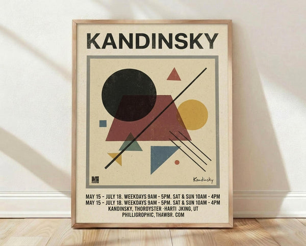 May include: Framed abstract geometric art print in light wood frame, leaning against white wall on wooden floor. Features cream background with black circle, red triangles, yellow circle, blue square, and intersecting black lines in Kandinsky's modernist style. Exhibition-style text below artwork shows dates and venue information.