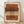 May include: Framed abstract art print leaning against white textured wall on light wood floor. Artwork features horizontal brushstrokes in terracotta, ochre, and brown tones with vertical column of black polka dots down center. Natural wood frame with warm earth-toned palette on cream background. Soft natural lighting creates diagonal shadows across wall.