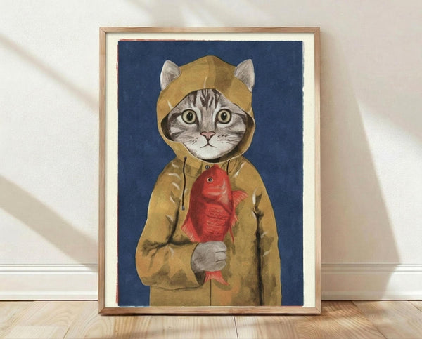 May include: Framed art print leaning against white wall on light wood floor. Shows tabby cat wearing mustard yellow hooded raincoat holding red fish, painted in whimsical illustrative style against deep blue background. Natural wood frame with white mat. Soft shadows from window light create gentle lighting across textured white wall.
