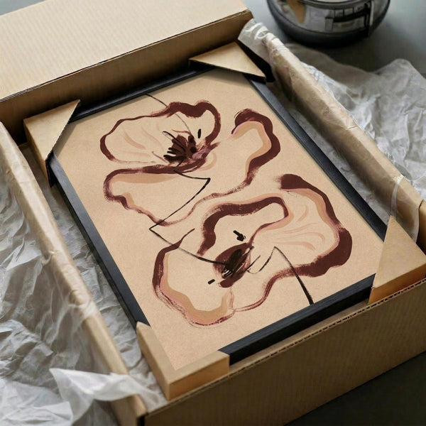 May include: Two framed botanical prints featuring abstract brown poppies with flowing, brushstroke-style petals and dark centers, displayed in black frames inside a cardboard shipping box with protective tissue paper and bubble wrap packaging materials visible around the edges.
