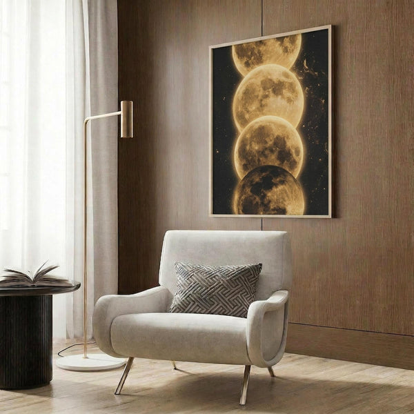 May include: Framed celestial artwork displaying four overlapping golden moons against a dark starry sky, hanging on wood-paneled wall above beige upholstered armchair with geometric patterned pillow. Modern reading corner features brass floor lamp and side table with open book near window with sheer curtains.