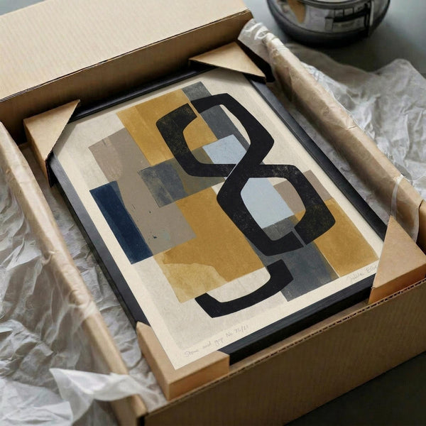 Abstract geometric artwork with overlapping rounded rectangular shapes in mustard yellow, charcoal black, sage green, and cream tones. The print is carefully packaged in a brown cardboard box with white tissue paper and wooden frame pieces visible alongside. Modern minimalist composition with organic flowing forms and muted earth tone color palette.