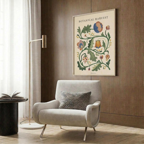May include: A framed botanical poster featuring colorful illustrated flowers, leaves, and berries in blues, oranges, and greens on a cream background, displayed on a wood-paneled wall above a beige upholstered armchair with geometric patterned pillow. Scene includes a brass floor lamp and small side table with an open book.