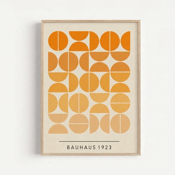 May include: Framed geometric art print with orange and cream colored circles and semicircles arranged in a grid pattern, displayed on a light gray wall. The minimalist design features warm orange tones graduating from bright to pale, with "BAUHAUS 1923" text below the composition. Natural wood frame surrounds the cream-colored background.