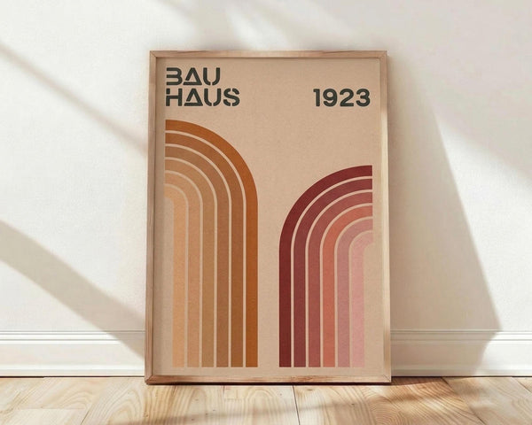 May include: Framed poster with geometric Bauhaus design featuring curved rainbow arcs in warm orange and burgundy tones against beige background, displayed on light wooden floor against white wall with natural window shadows