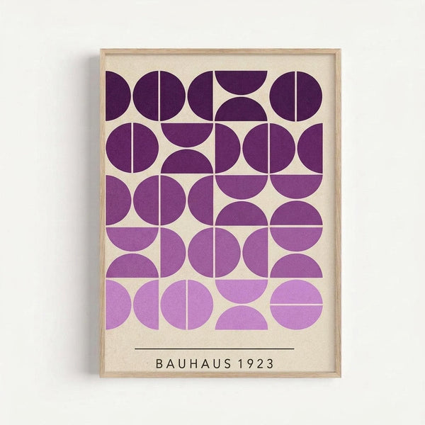 Framed geometric art print featuring purple circles and semicircles in various shades from deep plum to lavender, arranged in a grid pattern on cream background. The minimalist design shows overlapping and intersecting circular forms creating an optical rhythm. Text reads "BAUHAUS 1923" in black letters below the geometric pattern. Natural wood frame mounted on white wall.