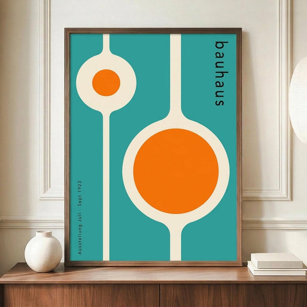 May include: Framed mid-century modern poster with turquoise background featuring two white organic shapes with orange circles, displayed on wooden sideboard next to white ceramic vase and books in elegant room with cream walls and white molding.