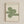 May include: Framed Bauhaus-style poster with green geometric design featuring flowing curved lines and spirals on cream background, displayed on white textured wall in light wooden frame