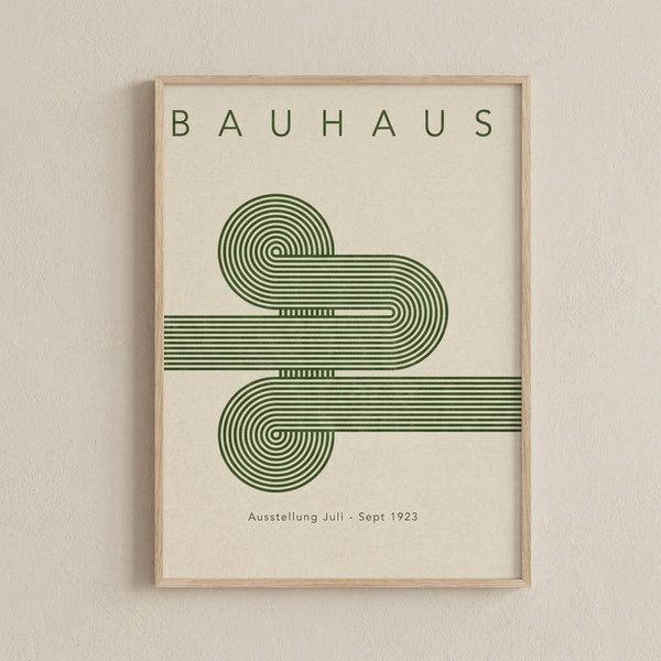 May include: Framed Bauhaus-style poster with green geometric design featuring flowing curved lines and spirals on cream background, displayed on white textured wall in light wooden frame