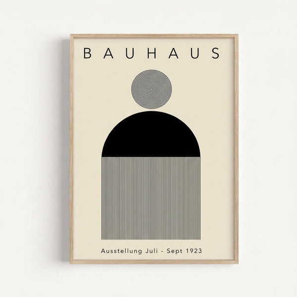 Minimalist geometric poster with "BAUHAUS" text at top and "Ausstellung Juli - Sept 1923" at bottom. Features three stacked shapes: small circle with concentric line pattern, large black semicircle, and rectangular section with fine vertical black and white stripes, all on cream background in light wood frame.