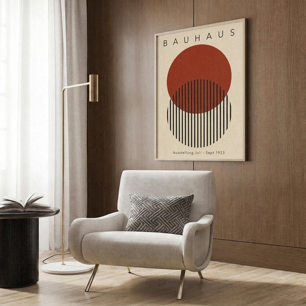 May include: Vintage Bauhaus exhibition poster print featuring geometric design with rust red circle overlapping black and white striped circle on cream background, displayed in modern living room with beige armchair, brass floor lamp, and wood paneled wall