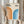 May include: Person in cream sweater holding framed Bauhaus-inspired print featuring orange and blue gradient arches on cream background, alongside dried wheat stems, against soft neutral curtained backdrop. Modern geometric art in light wood frame showcasing curved striped design in warm orange tones transitioning to cool blue hues.