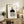 May include: Framed Bauhaus-inspired minimalist poster with geometric shapes - small circle with concentric lines, black semicircle, and striped rectangle on cream background. Displayed on rustic wooden sideboard with fern plant, books, ceramic vase, and leather sofa in neutral-toned living room setting.