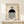 May include: Framed Bauhaus poster with geometric design featuring concentric circles, black semicircle, and vertical black and white stripes on cream background. Natural wood frame displayed on light wooden surface with small wrapped gift decorated with evergreen sprig against neutral wall.