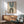 May include: Framed geometric poster with teal and brown arched shapes on cream background, displayed above wooden sideboard with white ceramic lamp in modern living room setting with mint green upholstered chair and round coffee table