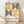 May include: Framed poster with geometric design featuring alternating black and golden yellow semicircular patterns arranged in a grid layout. Clean Bauhaus-style typography below the geometric elements. Light wood frame leaning against white wall on wooden floor with soft natural lighting creating diagonal shadows.