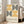 May include: Framed poster with geometric pattern of concentric semicircles in golden yellow and black on cream background, displaying "bauhaus-archiv" text below. Light wood frame leaning against white wall next to beige upholstered sofa in bright, naturally-lit living room with hardwood floors.