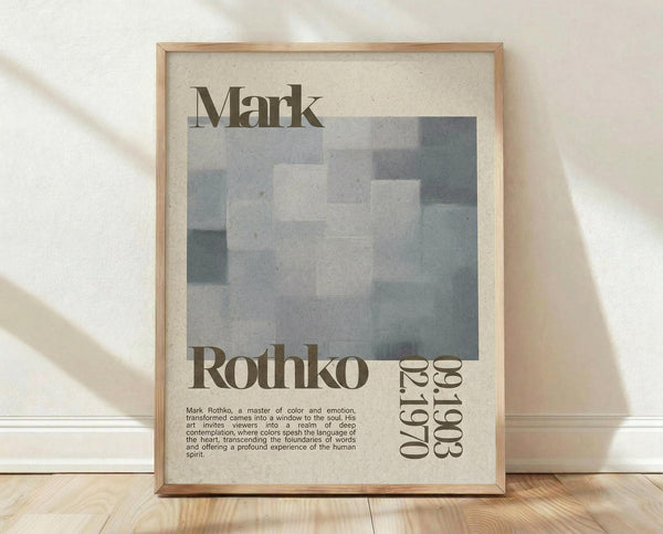 May include: Framed art print featuring Mark Rothko's name in large serif text above an abstract composition of soft gray and blue rectangular color blocks. Below shows "Rothko" and "1903-1970" with descriptive text about the artist. The beige poster has a light wood frame and leans against a white textured wall on wooden flooring, with natural shadows cast across the scene.
