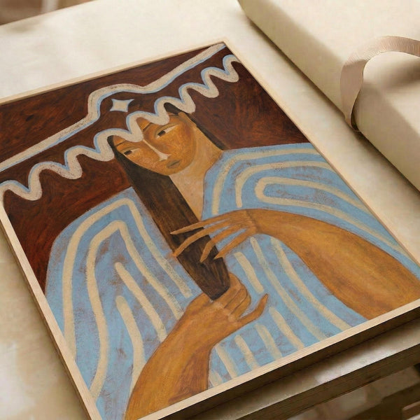 May include: Art print displayed on white upholstered furniture showing a woman with long dark hair and golden-brown skin tone against a burgundy background. The artwork features flowing blue and white curved lines throughout the composition, painted in an expressive style with warm earth tones. The print appears medium-sized relative to the cream-colored couch or chair beneath it.