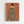 May include: Framed art print hanging on white wall showing woman from behind with dark hair in bun, wearing black and white striped cloak or blanket, small blue bird perched on her shoulder, warm orange-brown background, light wood frame, minimalist room setting