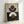 Framed geometric abstract art print featuring overlapping semicircles and circles in terracotta brown, cream, and navy blue colors. The artwork is displayed in a light wood frame against a white wall, showing the interplay of curved shapes against contrasting backgrounds in the upper and lower sections of the composition.