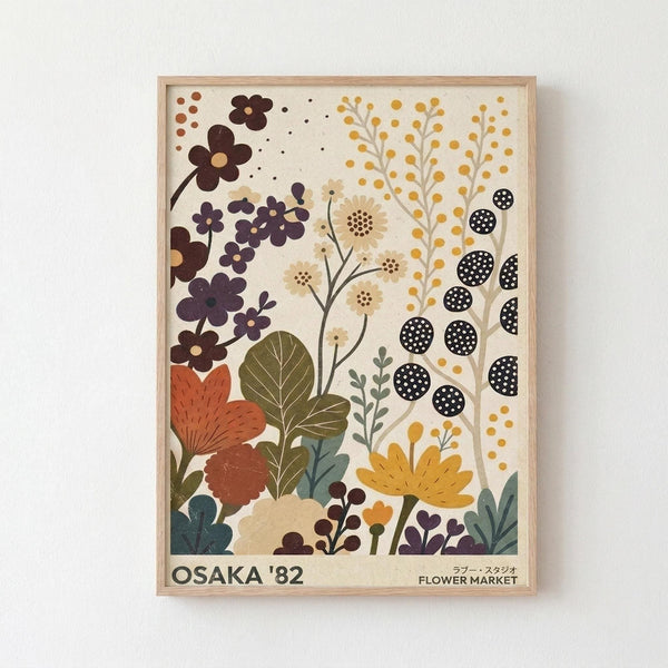 Framed botanical poster with stylized flowers and plants in earth tones including rust orange, deep purple, olive green, and golden yellow against cream background. Features various floral motifs like daisies, berries, leaves, and dotted circular patterns in folk art style. Text reads "OSAKA '82 FLOWER MARKET" at bottom. Light wood frame against white wall.