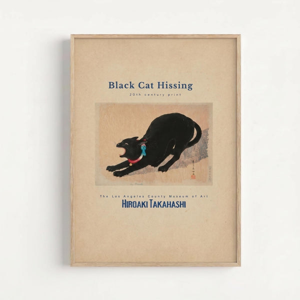 A framed museum poster featuring a Japanese woodblock print of a black cat in an aggressive hissing pose with arched back and open mouth, wearing a red collar with blue accent. The artwork is set against a beige background with Japanese characters and red seal stamp. The poster includes museum text identifying it as a 20th century print by Hiroaki Takahashi from The Los Angeles County Museum of Art. The piece is displayed in a light wood frame against a white wall.