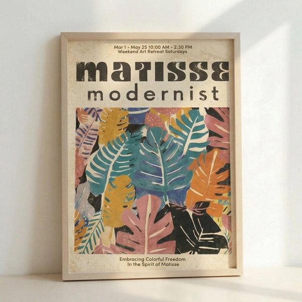 May include: Framed poster with colorful tropical leaf cutout design in Matisse style, featuring overlapping monstera and palm leaves in teal, orange, pink, yellow and black. Light wood frame displayed against white wall. Text at top reads "Mar 1 - May 25 10:00 AM - 2:30 PM Weekend Art Retreat Saturdays" and "modernist" below artist name. Bottom text says "Embracing Colorful Freedom In the Spirit of Matisse."