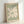 May include: Framed art print in light wood frame leaning against white wall. Green background with large white flower cutout design in Matisse's paper collage style. Text reads "MATISSE" at top and "PAPIERS DÉCOUPÉS" at bottom in dark letters. Simple daisy-like bloom with rounded petals and organic center shape fills most of the composition.