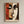 May include: Framed art print featuring a cubist-style portrait with geometric faces in warm earth tones - rust red, cream, and brown. The abstract composition shows fragmented facial features with prominent eyes, angular shapes, and overlapping planes. Text reads "PICASSO" and "interpretation artistique d'après l'œuvre de Pablo Picasso" at bottom. Natural wood frame against neutral beige wall.