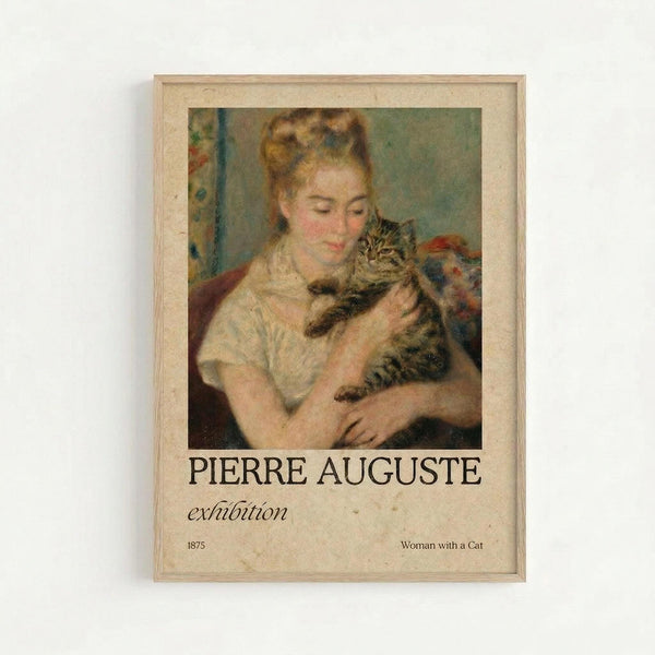 A framed exhibition poster featuring Renoir's 1875 painting "Woman with a Cat" showing a young woman in a white dress holding a tabby cat. The artwork displays soft, impressionistic brushstrokes in warm tones of peach, cream, and muted greens. Below the painting reproduction is black text reading "PIERRE AUGUSTE exhibition" with "1875" and "Woman with a Cat" in smaller text. The poster has a cream-colored matted border within a light wooden frame, mounted on a whi