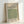 May include: Framed vintage-style poster with cream background featuring green geometric diaper pattern design by William Morris. Shows grid of repeating circular and square motifs in muted sage green. Dated 1870 with Smithsonian Institution attribution. Natural wood frame sits against white wall with soft shadows, displaying the decorative Arts and Crafts movement wallpaper pattern in an elegant home decor setting.
