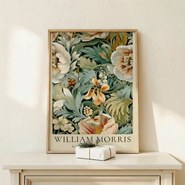 May include: Framed botanical art print featuring William Morris-inspired floral design with cream peonies, sage green foliage, and orange accent flowers against dark background, displayed on light wood console table beside small wrapped gift with twine and sprig decoration against neutral wall