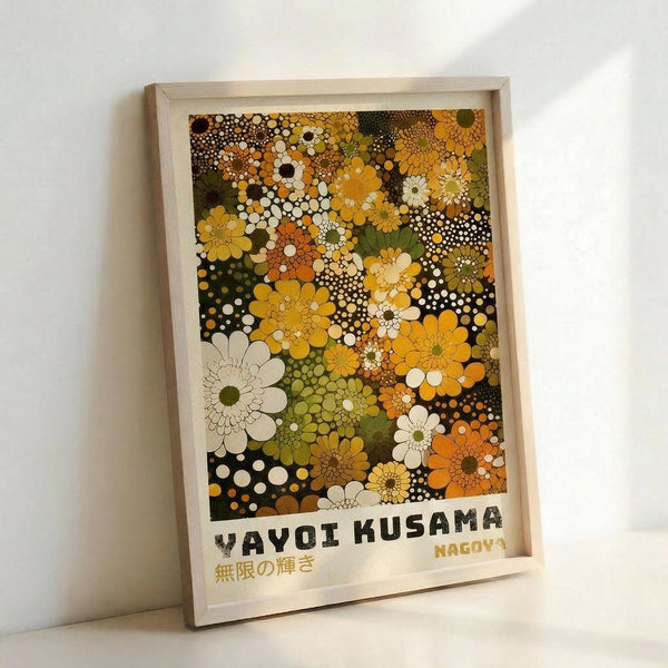 Framed art print featuring abstract floral pattern in warm earth tones including yellows, oranges, greens, and browns. The design shows overlapping stylized flowers and dotted circular patterns creating a dense, psychedelic composition. Text at bottom reads "YAYOI KUSAMA" in black letters and "NAGOYA" in yellow, with Japanese characters below. Print is displayed in light wooden frame leaning against white wall.