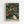 Framed poster featuring an abstract design with swirling green brushstrokes and colorful polka dots in yellow, orange, red, blue, and white circles of various sizes scattered across a dark green background. The artwork includes a large cream-colored organic shape filled with multicolored dots in the lower right. Text reads "YAYOI KUSAMA" in bold black letters with Japanese characters below and "TOKYO" in smaller text. The poster is displayed in a light wood frame against a white wall.