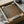 May include: Brown and beige abstract dotted poster print displayed in black frame, partially unboxed with cardboard packaging and protective tissue paper on white surface. Artwork features organic curved shapes created with stippled dot pattern in earth tones.