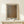 May include: Framed art print leaning against cream wall on light wood console table, featuring abstract brown and beige dotted pattern with "Tokyo 1998" and Japanese characters at top, "YAYOI KUSAMA" text at bottom. Small white gift box with greenery sits in front. Natural wood frame with white matting.
