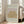 May include: Framed vintage-style art print leaning against white wall in bright living room with beige sofa. Poster features golden yellow botanical leaf pattern on pink background with "MATISSE" text at top and French gallery text below. Light wood frame, natural lighting from windows.